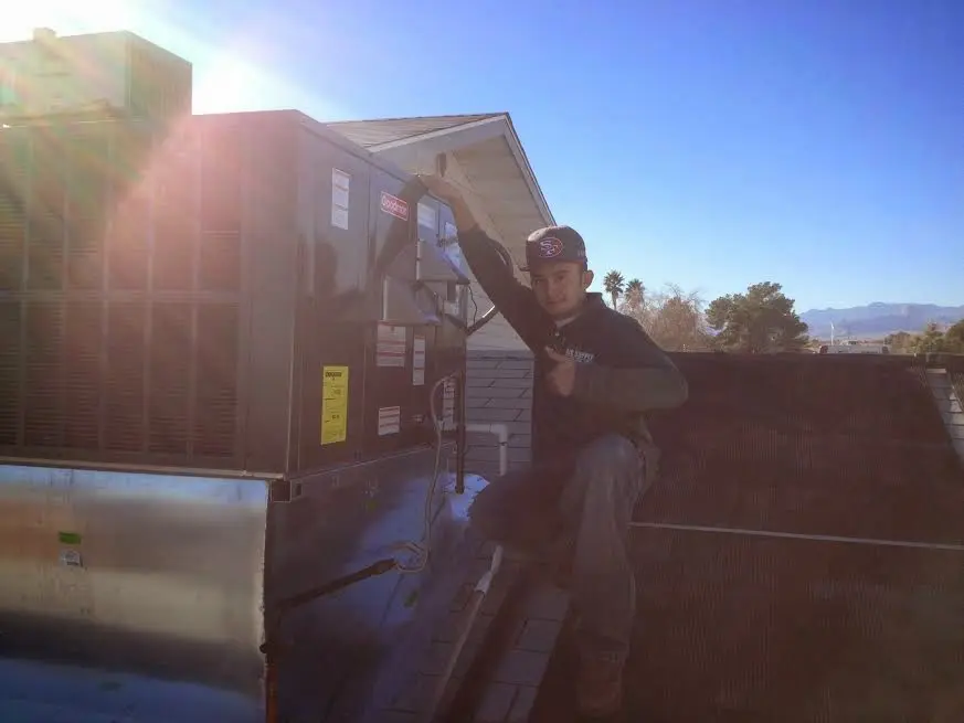 HVAC technician performing Heat Pump Repair on a rooftop unit in Weisenberg